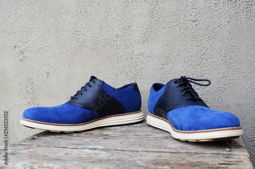 Dark blue sneakers with a white sole on a wooden background