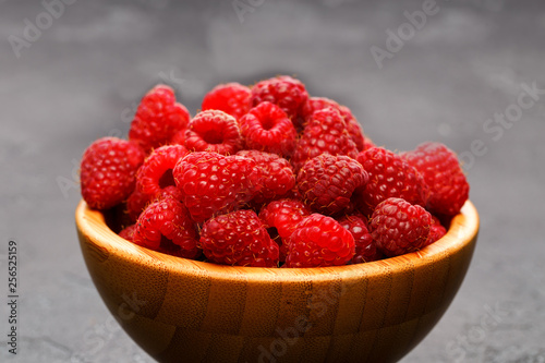 Photo of raspberries in wooden cup on black background