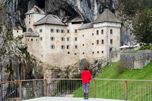 Young woman is admiring the magnificent Predjama Castle which is one of the most famous landmarks in Slovenia, attracting  thousands of tourists each year.