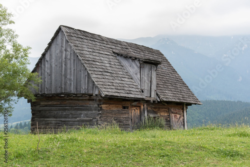 Old wooden barn in field with mountains in background