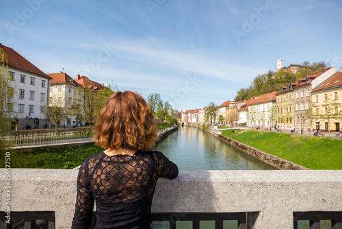 Young woman is admiring old buildings, apartments and castle in old part of Ljubljana, Slovenia