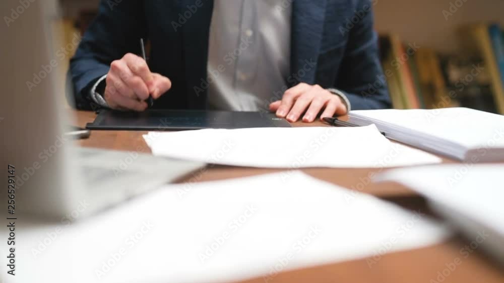 Close up of professional man sitting at table in office using digital tablet – creative business, designer, technology concept Close up of professional man sitting at table in office using digital tablet – creative business, designer, technology concept