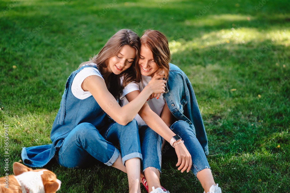 Two friends are sitting on the green lawn in the park. Two friends are sitting on the green lawn in the park.