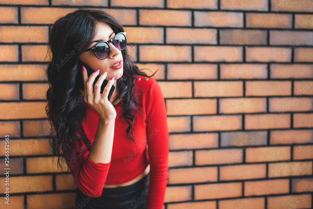 Attractive dark-haired young woman on the street near the brick wall Attractive dark-haired young woman on the street near the brick wall