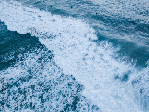 Aerial view of wave breaking into white foam.