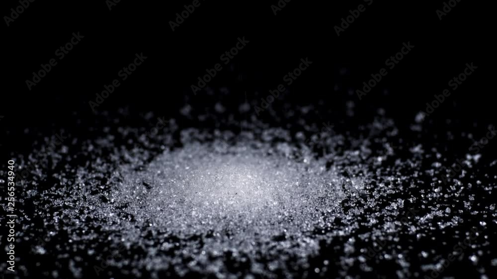 A stream of sugar pours down onto a reflective back surface growing into a pyramid pile against a black background. Great for projects about health and food. A stream of sugar pours down onto a reflective back surface growing into a pyramid pile against a black background. Great for projects about health and food.