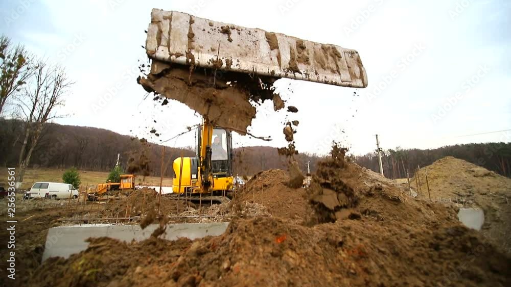 Slow motion of a digger digging a pit and throwing dirt. Closeup of a