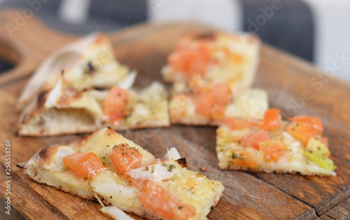 Italian crostini with tomato, onion, garlic, oregano and olive oil on wheatered wooden cutting board. Selective focus