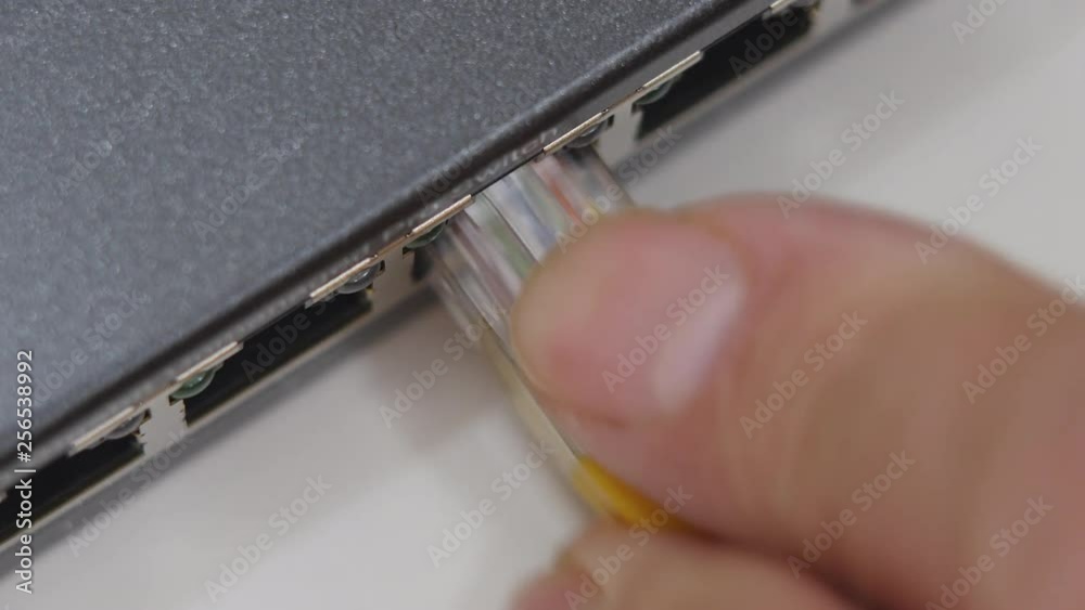 Male Hand Inserts Yellow Data Cable Into The Gigabit Network Switch. Male Hand Inserts Yellow Data Cable Into The Gigabit Network Switch.