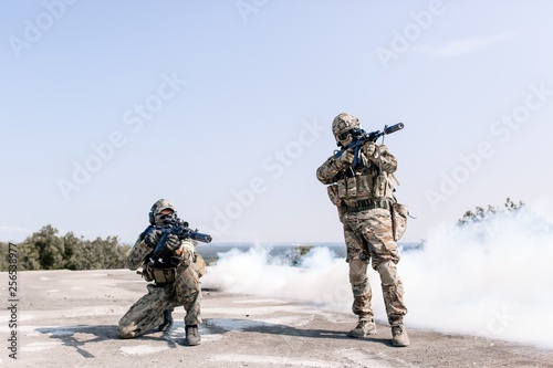 Military with sniper rifles preparing to fire on the enemy standing in the open air