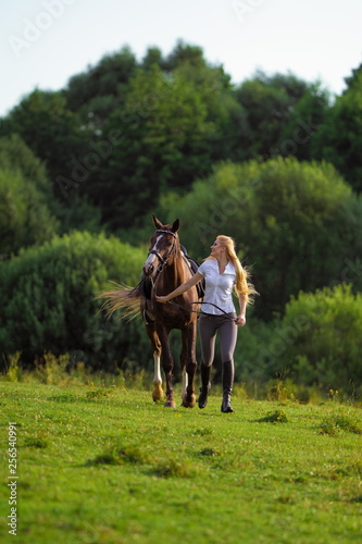 Young blond woman with long hair, cowboy in a pen with horses on the ranch photo