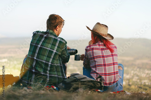 Couple of young attractive backpackers having rest after achieving mountaing top photo