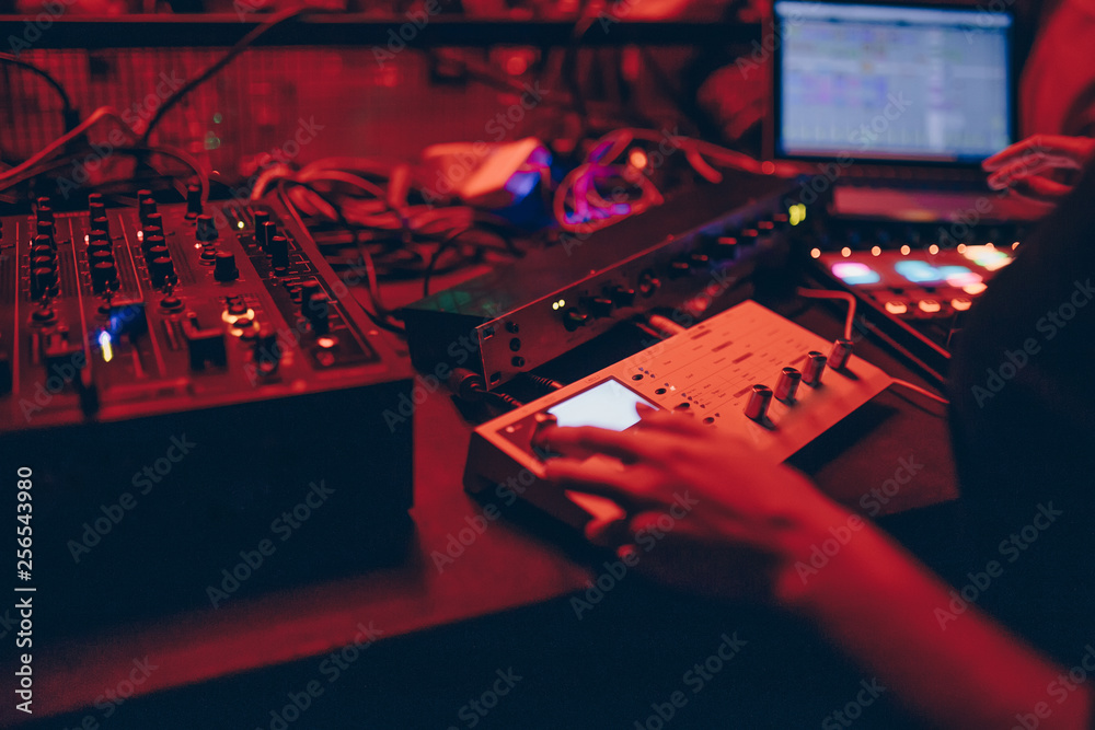 producer  DJ mixer in a nightclub with glowing plays musical rave Dubstep Electronic Trance composition with modern midi controller device in nightclub Live.Musical production process for artists. - obrazy, fototapety, plakaty 
