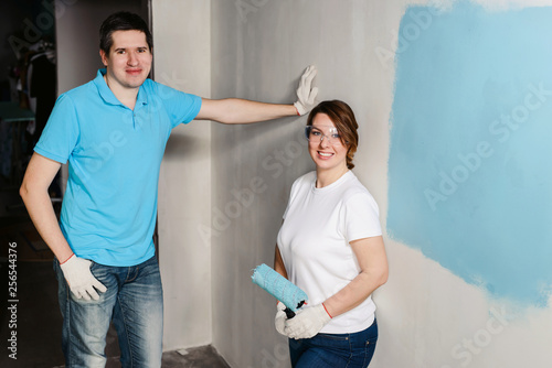 Young happy couple painting their new house interiors using paint rollers Home makeover and renovation concept