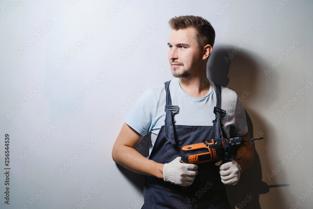 Half-length portrait of foreman worker in uniform handing drill and hammer, isolated on white. Concept of restoration and engineering home renovation Half-length portrait of foreman worker in uniform handing drill and hammer, isolated on white. Concept of restoration and engineering home renovation