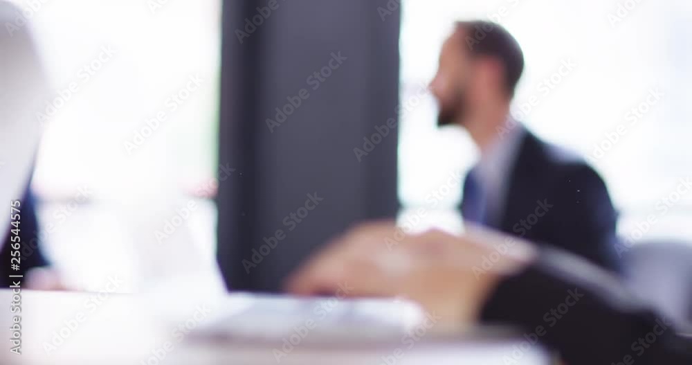 4K Corporate business team at work with focus pull from background to foreground. Slow motion.