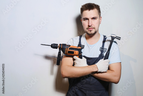 Half-length portrait of foreman worker in uniform handing drill and hammer, isolated on white. Concept of restoration and engineering home renovation © ANR Production