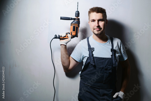 Half-length portrait of foreman worker in uniform handing drill and hammer, isolated on white. Concept of restoration and engineering home renovation