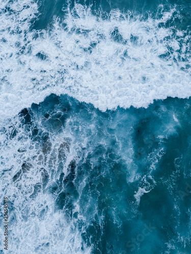 Top down aerial view of waves breaking into white foam.
