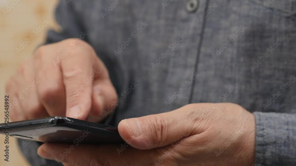 Elderly Man In The Grey Shirt Is Typing On Smartphone. Slider Shot Elderly Man In The Grey Shirt Is Typing On Smartphone. Slider Shot
