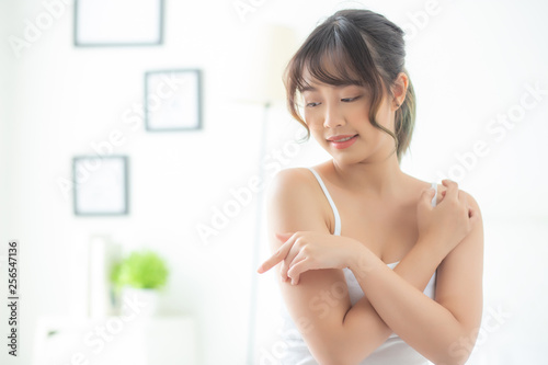 Portrait of beautiful young asian woman makeup of cosmetic  girl hand touch shoulder and smile attractive  face of beauty perfect with wellness in the bedroom with skin care and healthcare concept.
