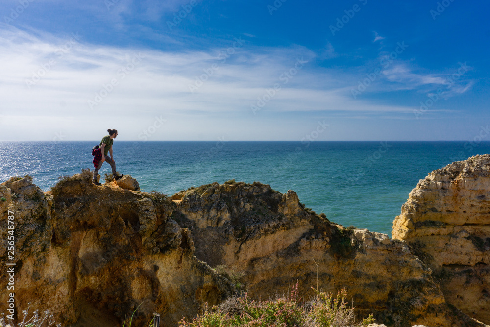 Young man on ridge looks down into ocean in Portugal