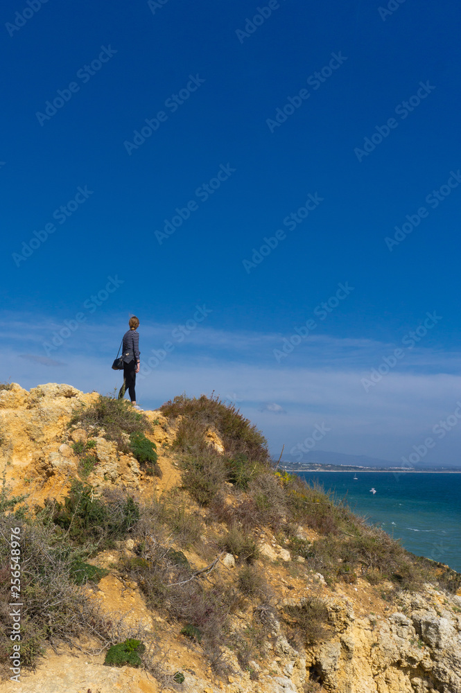 Female hiker looking out over ocean from ridge in Portugal