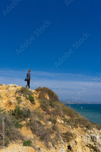 Female hiker looking out over ocean from ridge in Portugal