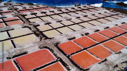 24 November 2018 La Palma Canary Islands, Salinas Marinas de Fuencaliente, Salts Flats and Mine showing multi coloured salt water fields aganst blue sky and waves photo