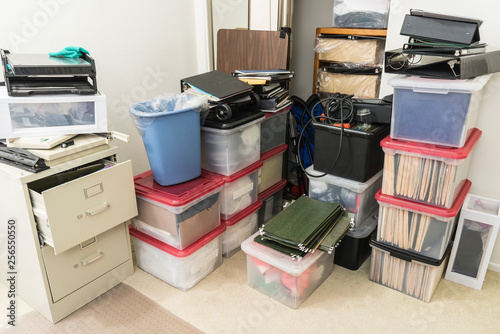 Cluttered corner with storage boxes, binders and miscellaneous office supplies.  