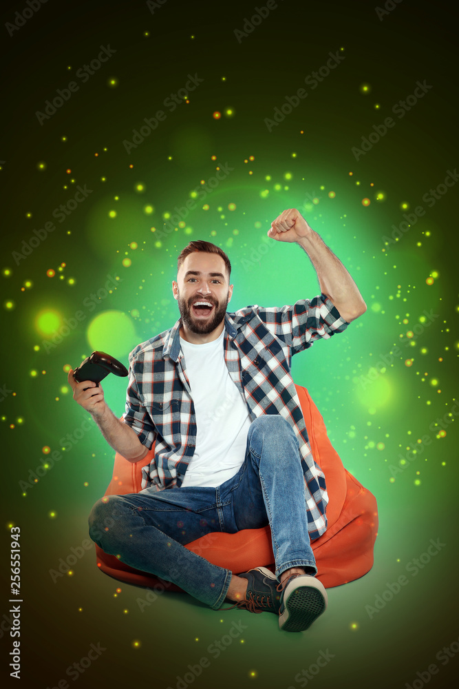 Naklejka premium Emotional man playing video games on color background