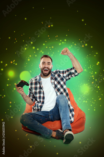 Emotional man playing video games on color background