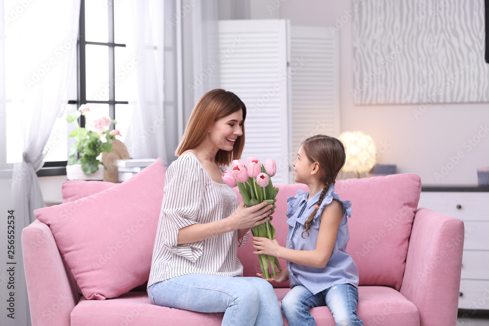 Happy mother and daughter with flowers at home. International Women's Day
