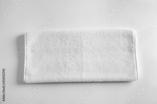 Folded soft terry towel on light background, top view