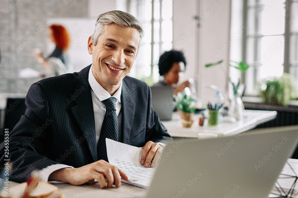 Happy businessman analyzing business reports in the office.