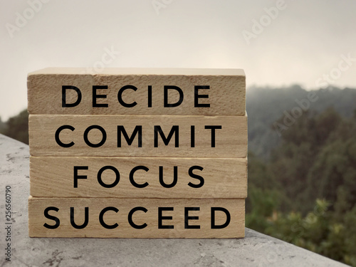 Motivational and inspirational words - Decide, Commit, Focus,Succeed written on wooden rectangular blocks.