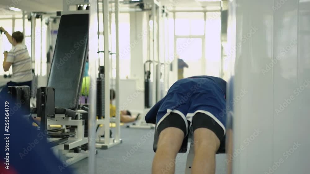 Person does the exercise hyperextension . Classes are held in the sports hall for people with disabilities.