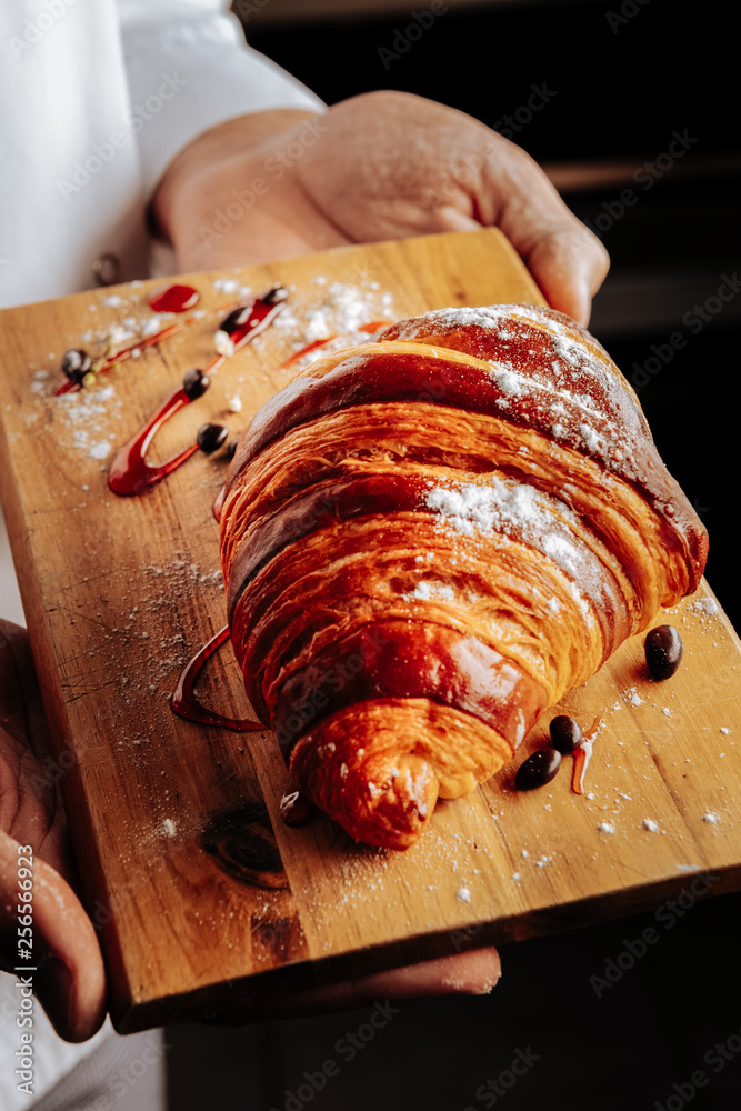 Fotografie Croissant with sugar powder on little wooden plate