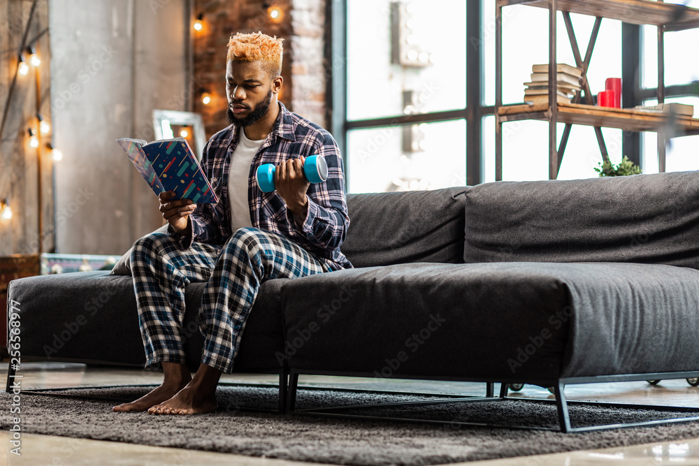 Obraz premium Nice serious man studying a book about sport
