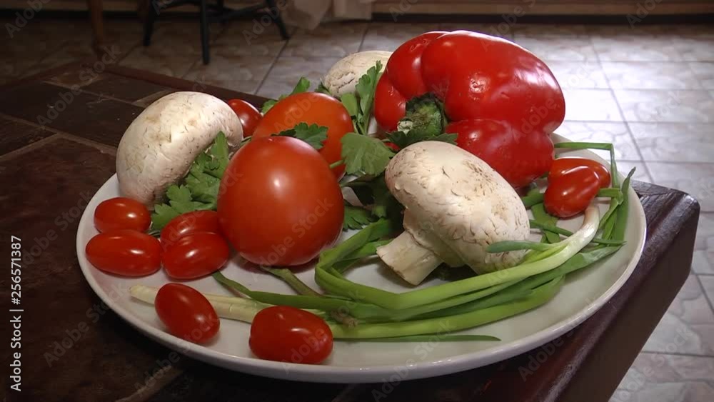 On a white plate are mushrooms, tomatoes, red peppers, green onions and parsley. Video filming with hands without stabilization. On a white plate are mushrooms, tomatoes, red peppers, green onions and parsley. Video filming with hands without stabilization.