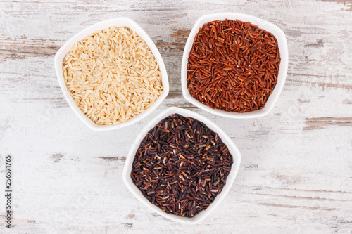 Black, red and brown rice in bowls, healthy gluten free food concept