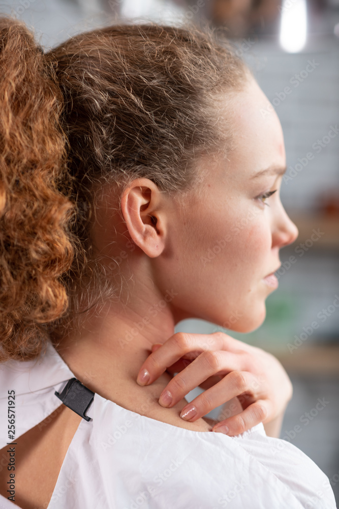 Annoyed curly-haired good-looking woman scratching her back Annoyed curly-haired good-looking woman scratching her back