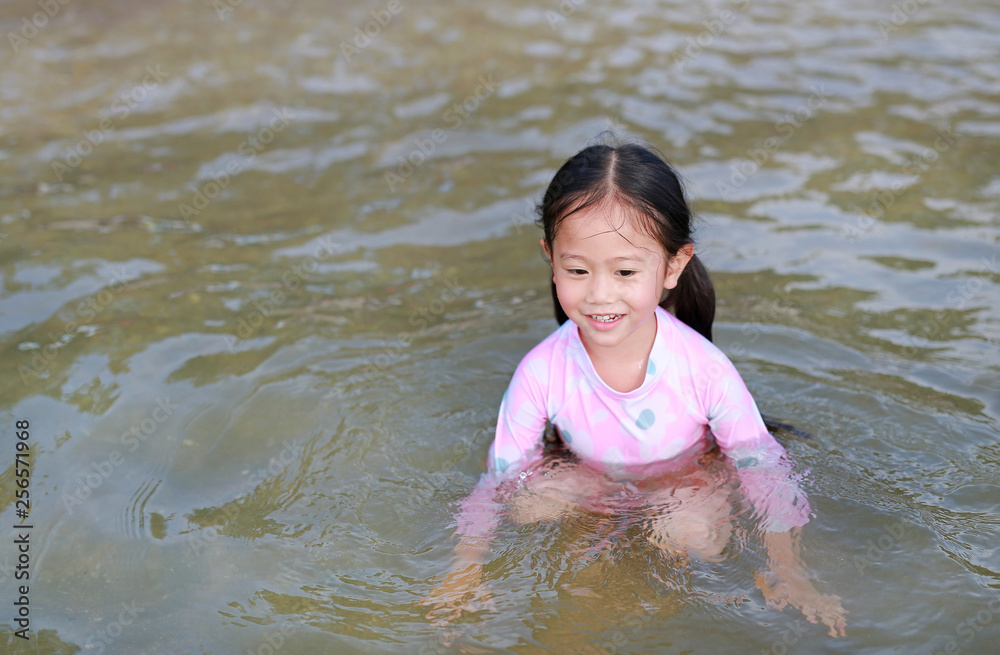 Happy little Asian girl in swimming suit playing water in a sea. Happy little Asian girl in swimming suit playing water in a sea.