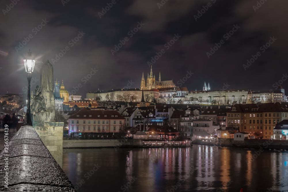 night image of Prague castle from Charles bridge with river in the foreground