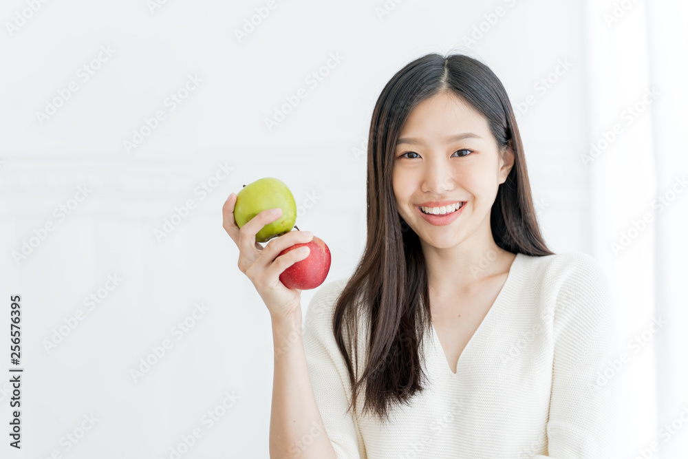 Young Asian woman showing green apple and red apple, indoors portrait Young Asian woman showing green apple and red apple, indoors portrait
