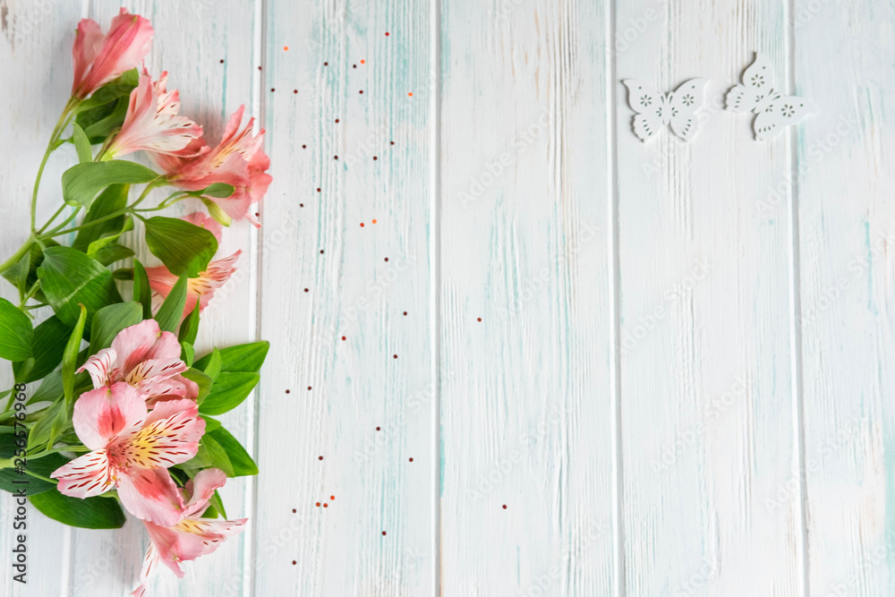 Fototapeta premium Background for text banner on a white wooden background with pink flowers and butterflies. Blank, frame for text. Greeting card design with flowers. Aalstroemeria on wooden background. View from above