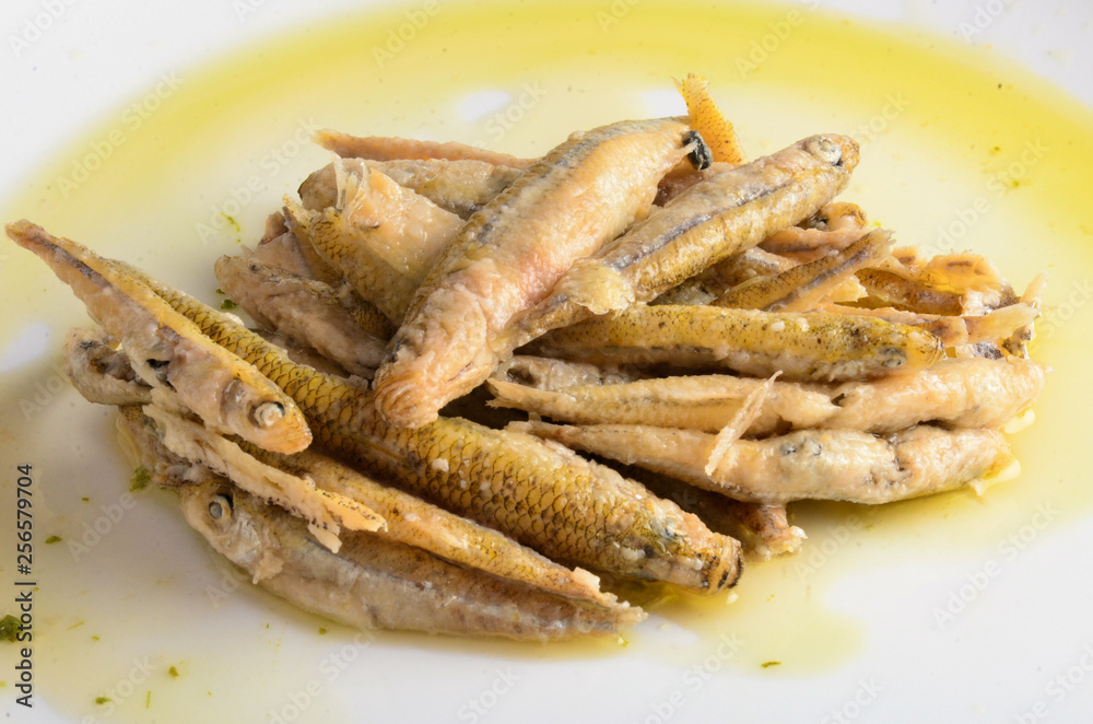 Fried fish with oil on a white plate
