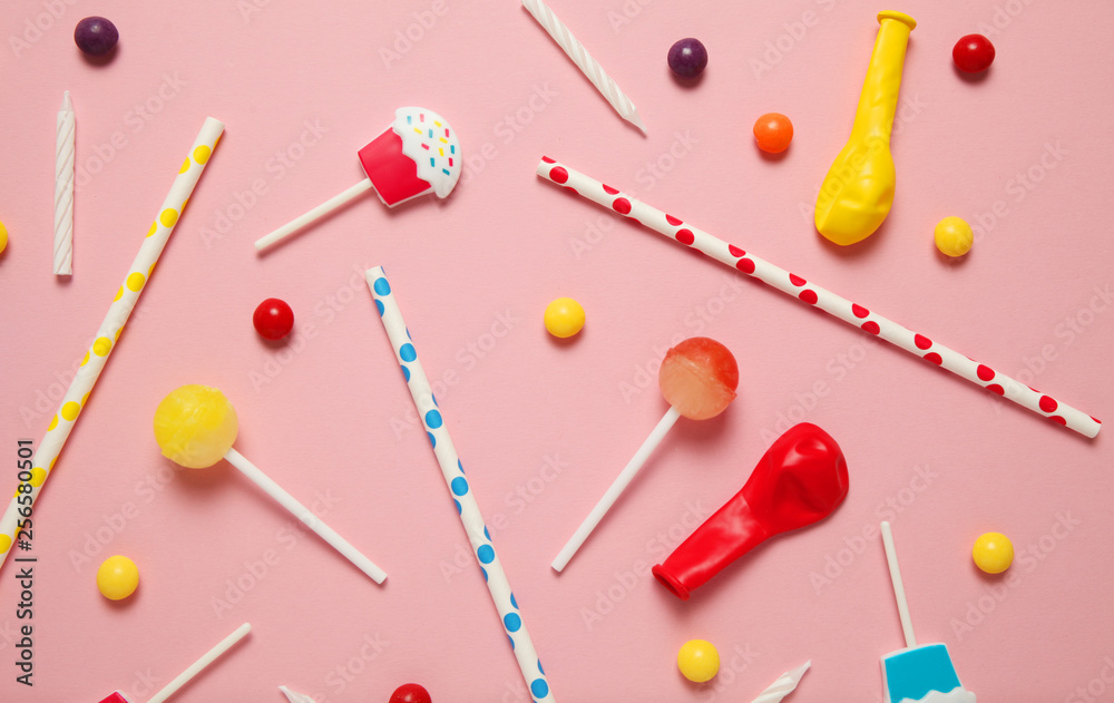 Children's cheerful decor for a party, pink background. Sweet candies, bright balls, festive candles and straws. Children's cheerful decor for a party, pink background. Sweet candies, bright balls, festive candles and straws.