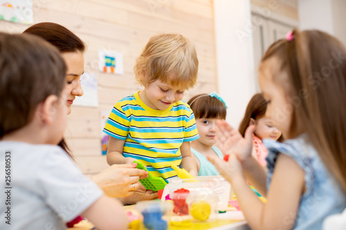 Teacher teaches kids modeling clay in playroom at daycare or kindergarten