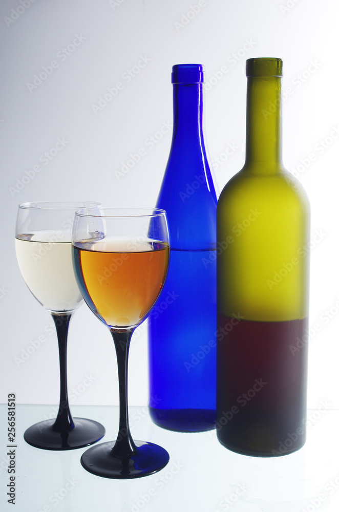 Two glasses of wine and two bottles on a light Two glasses of wine and two bottles on a light